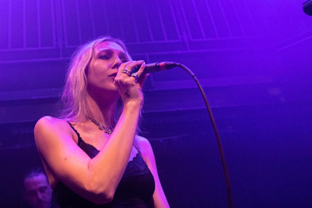 Lyza Jane sings into the microphone in a black top.