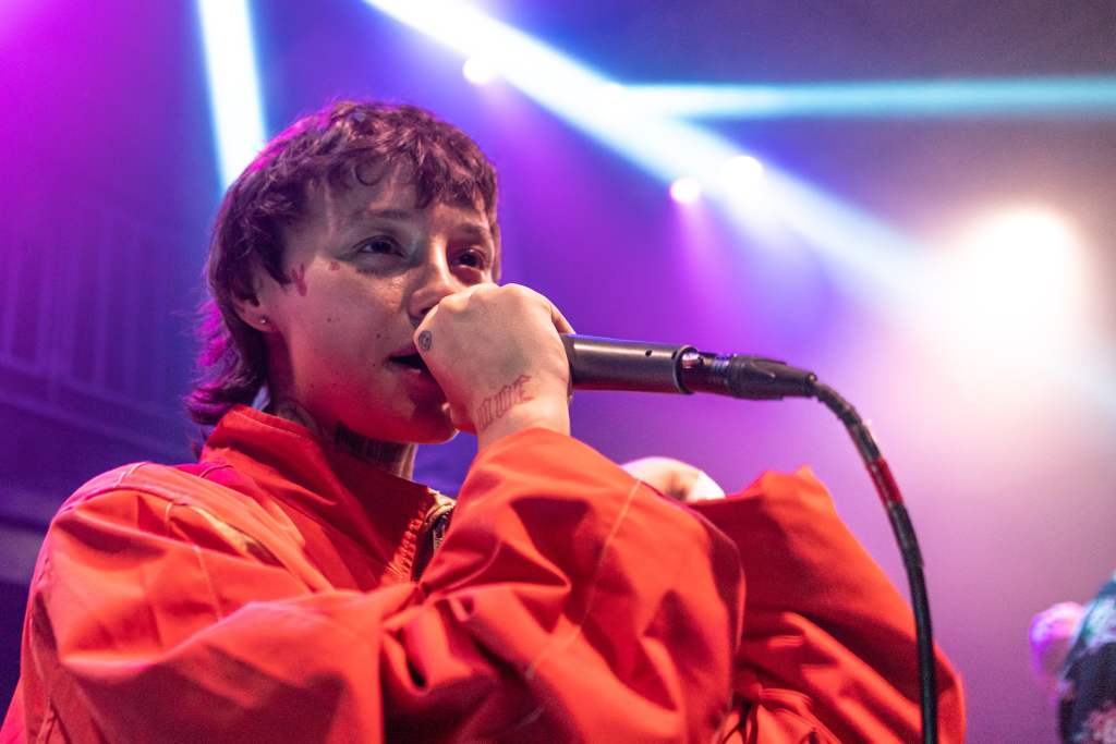 CHLOBOCOP raps into the microphone wearing an all-red jacket.