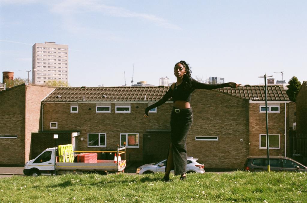 Landscape photo of Jaydonclover in front of houses, stood with open arms on the grass.